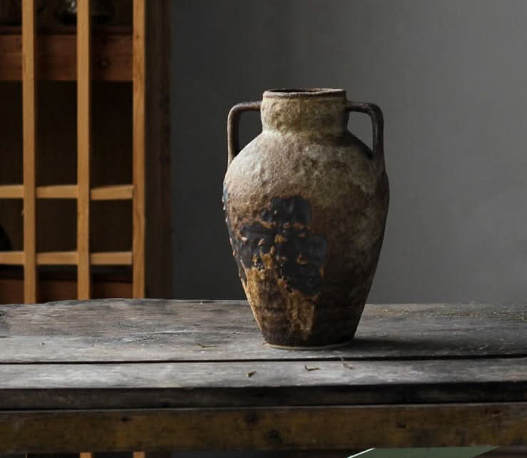 Wabi-sabi small ceramic vase with textured, earthy tones on a wooden surface.