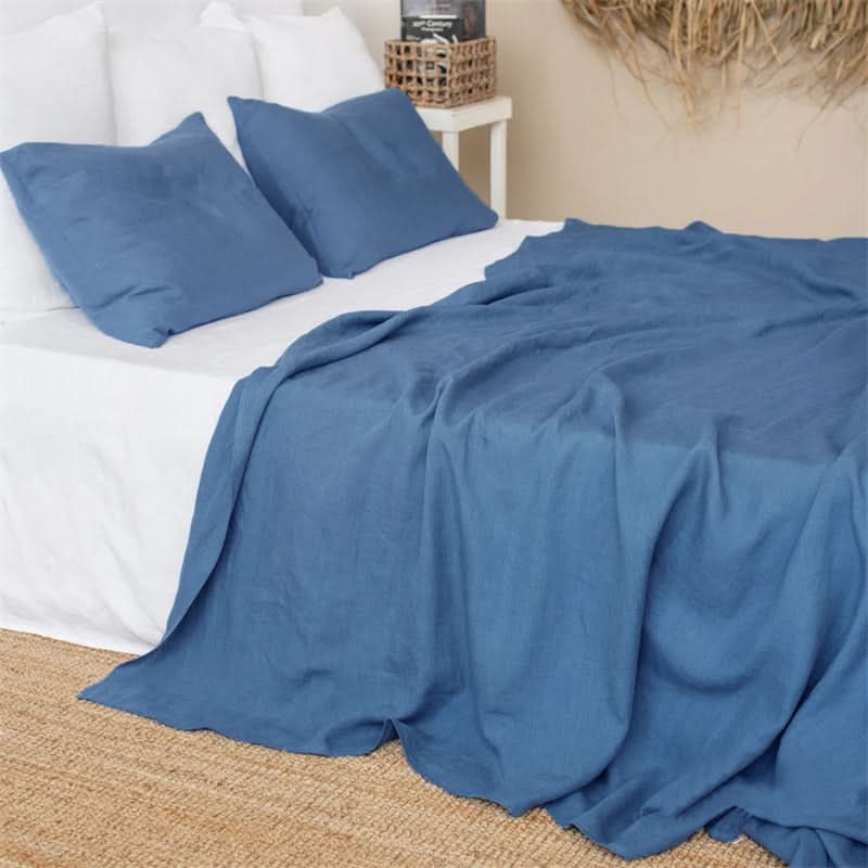 Blue linen bed sheets and pillowcases on a white sheet, on a bed.