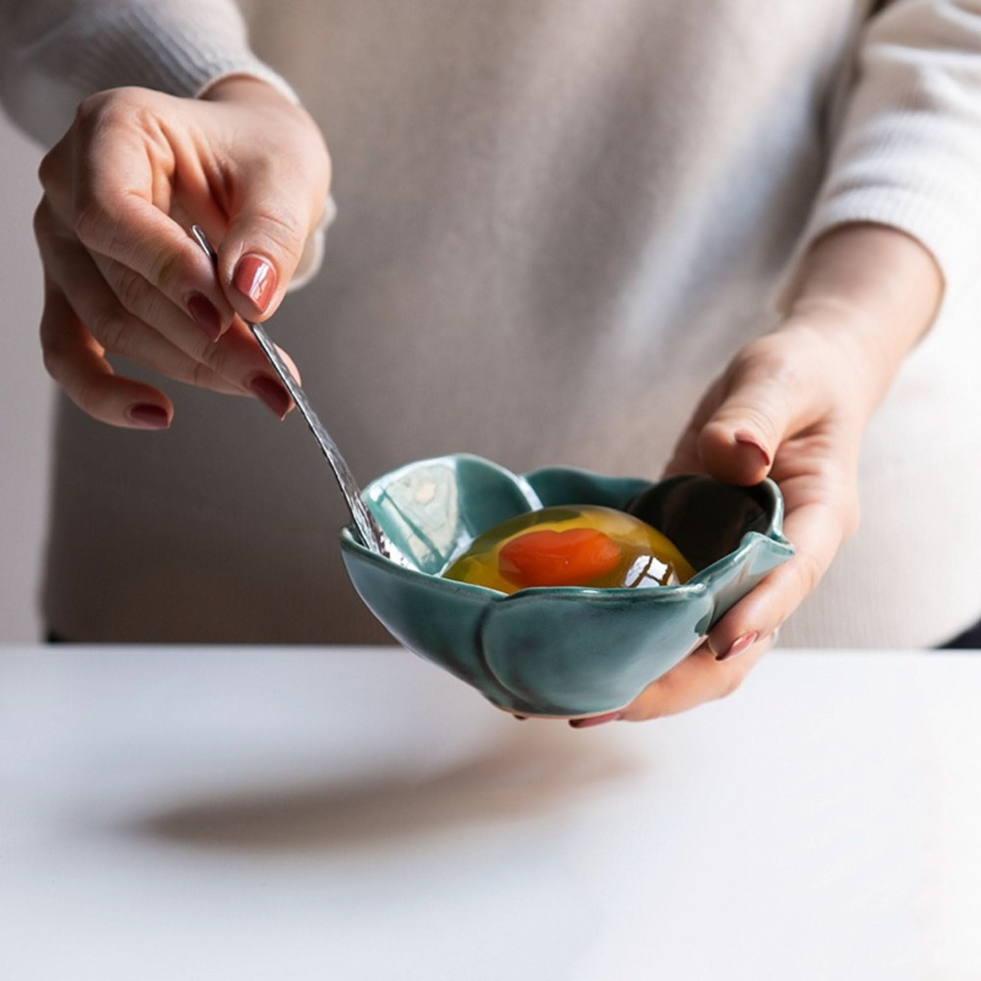 Teal ceramic Camellia sauce bowl, handmade in Japan, holds a raw egg and yolk with a fork.