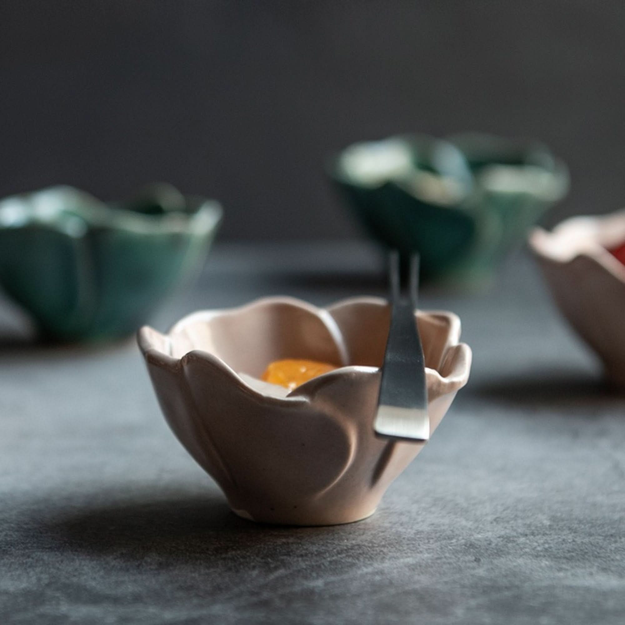 Handmade ceramic Camellia sauce bowl, beige, with fork, on dark surface.