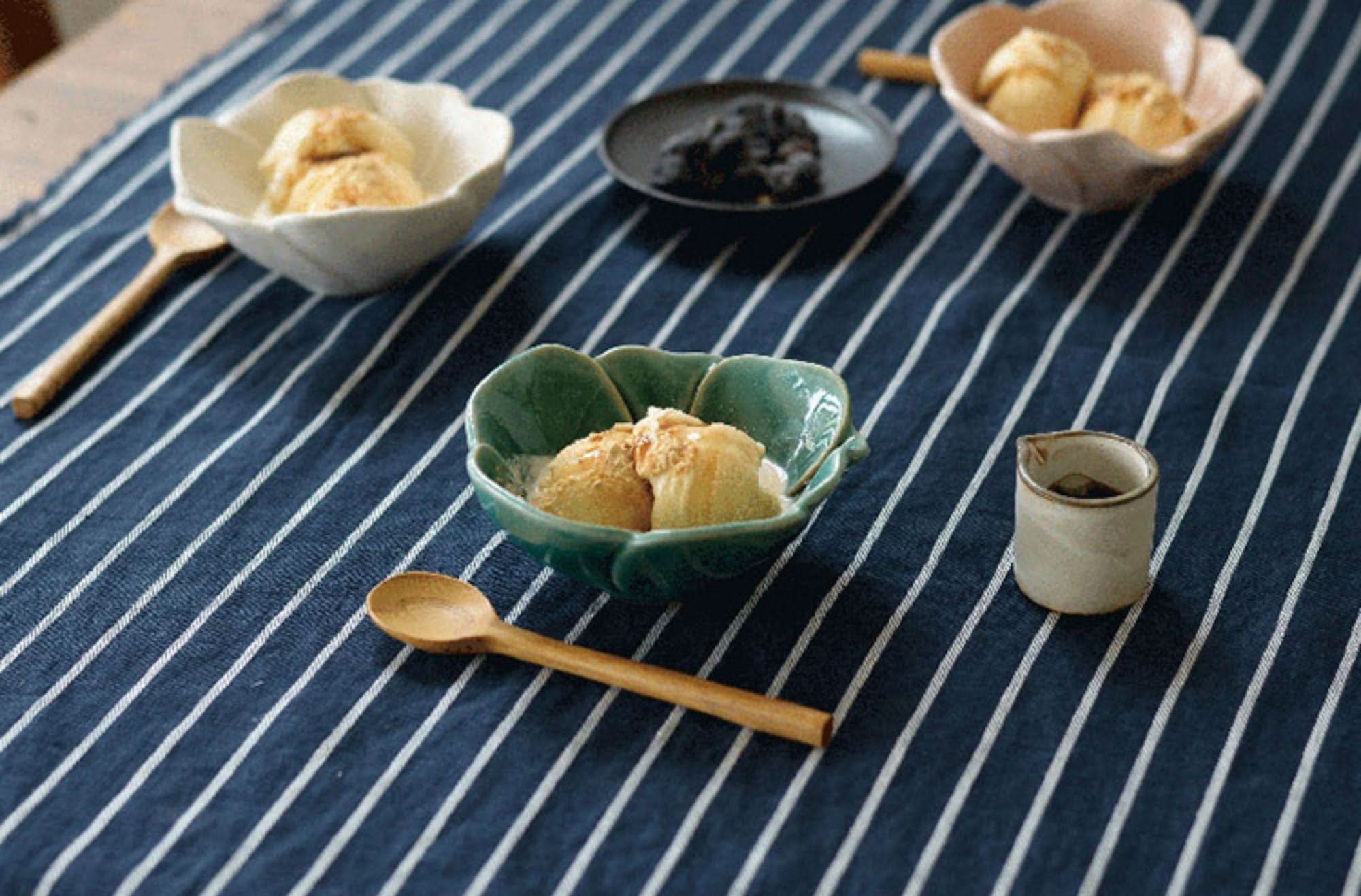 Camellia Ceramic Sauce Bowl filled with ice cream, on a striped cloth with wooden spoons.