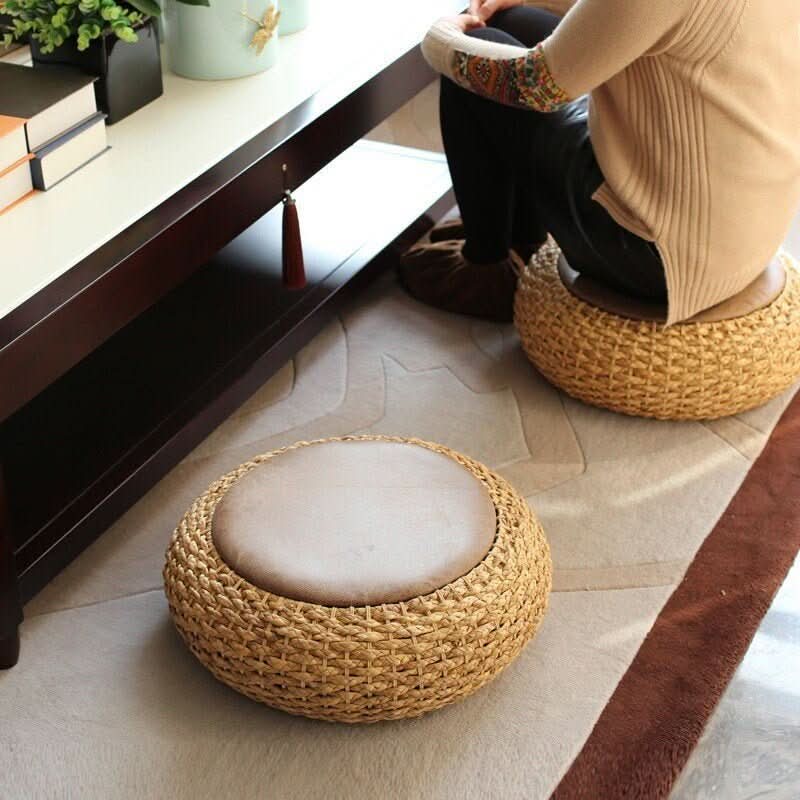 Natural cattail woven round futon with tan cushion on a rug, near a coffee table.