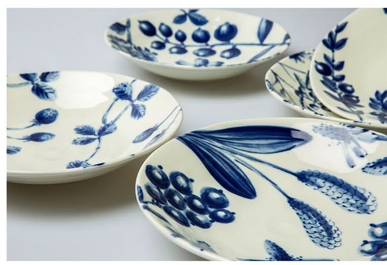 Cream ceramic tableware with blue hand-painted botanical designs. Japanese art.