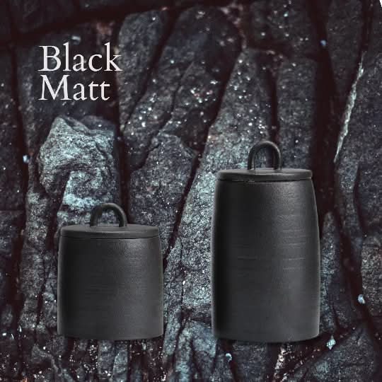 Black matt ceramic tea canisters with handles on textured rock background.