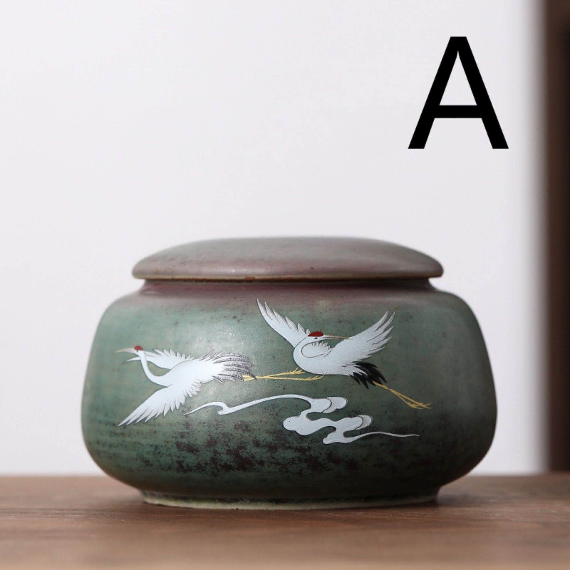 Ceramic tea can with Japanese crane illustration in green, perfect storage jar for kitchen organization.