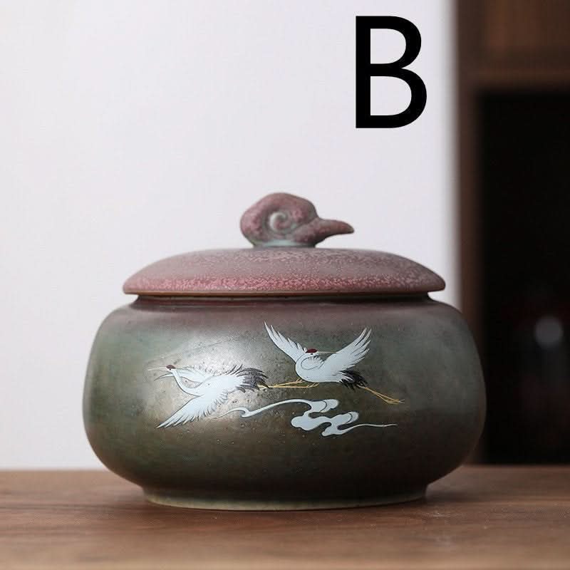 Ceramic tea can with Japanese art illustration, green storage jar with cranes on wood table.