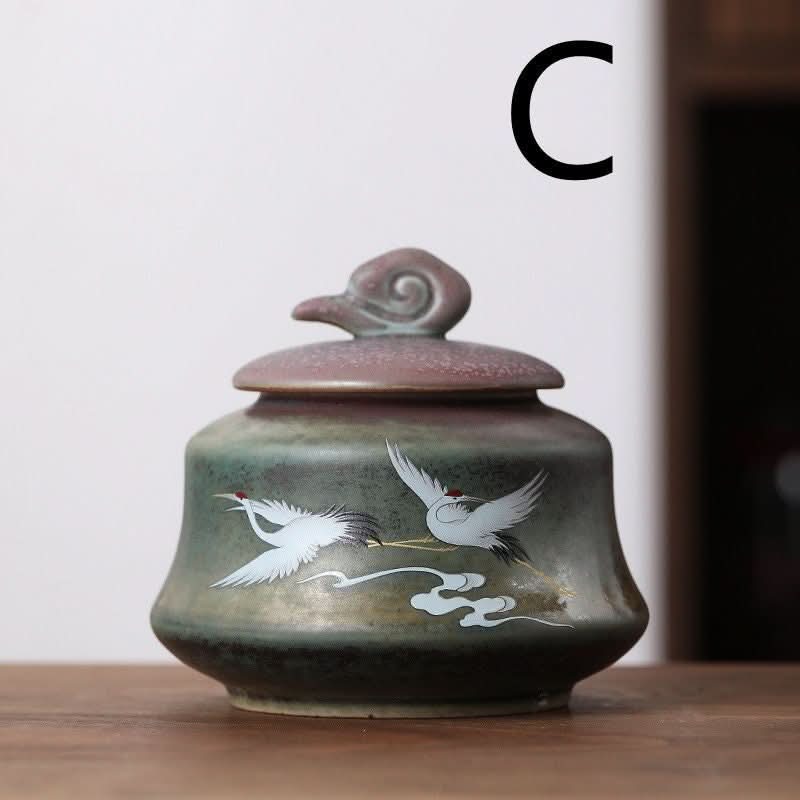 Ceramic tea can with Japanese cranes illustration in green and brown hues.