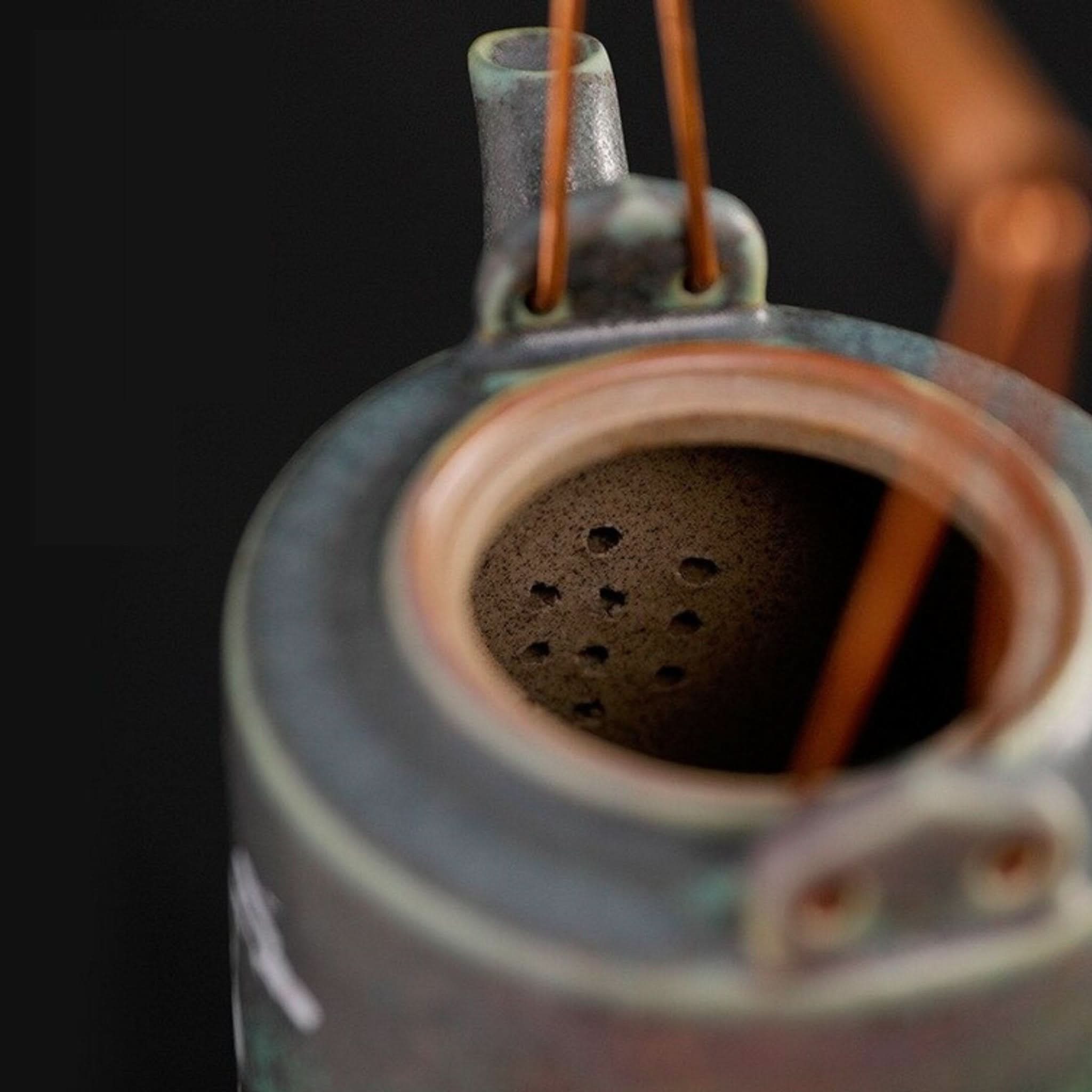 Ceramic tea pot with Japanese style crane detail, featuring a brown interior with strainer holes.