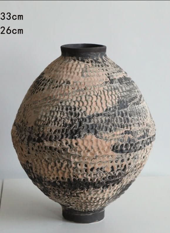 Ceramic vase with hammered circular texture in beige and black with brushed effect.