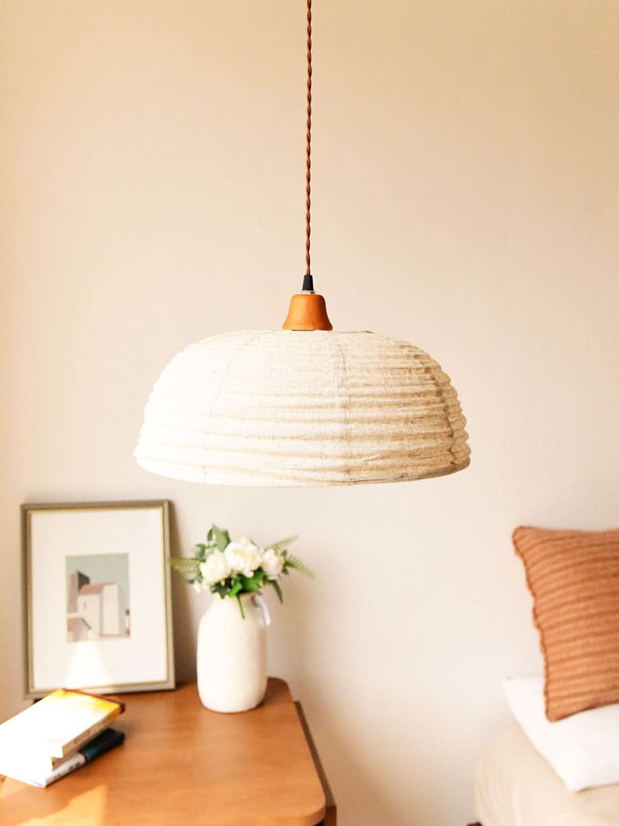 Dome lampshade with natural hemp fabric, hanging in a room with a framed picture and flowers.