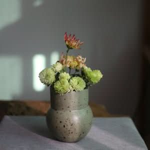 Clay Handmade Large Vase Rounded Vase with soft green and pink flowers on textured surface.