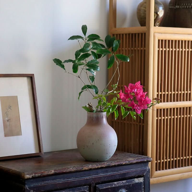 Light grey Clay Handmade Large Vase Rounded Vase with pink flowers on rustic table.
