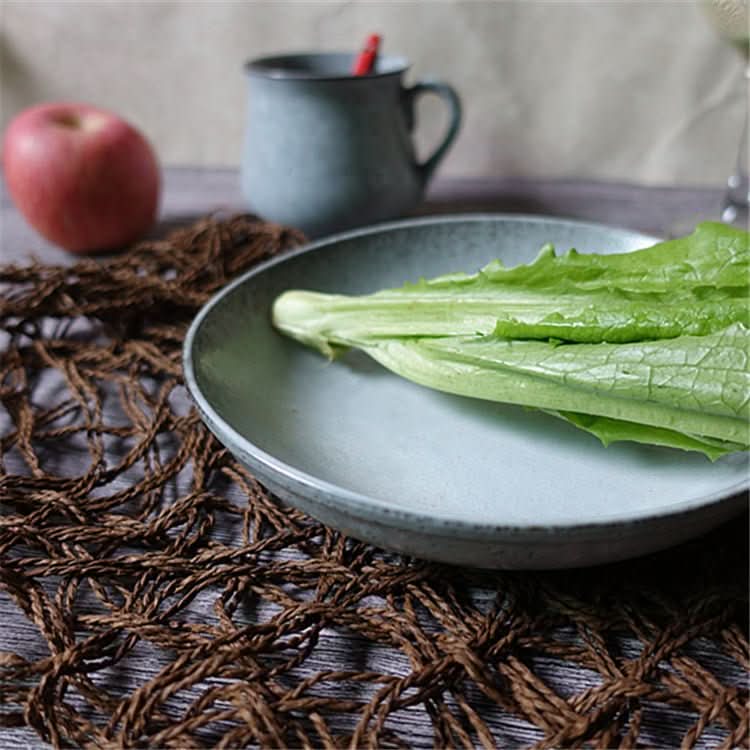 Cyan blue glazed ceramic plate with speckles, holding lettuce. Rustic table setting.