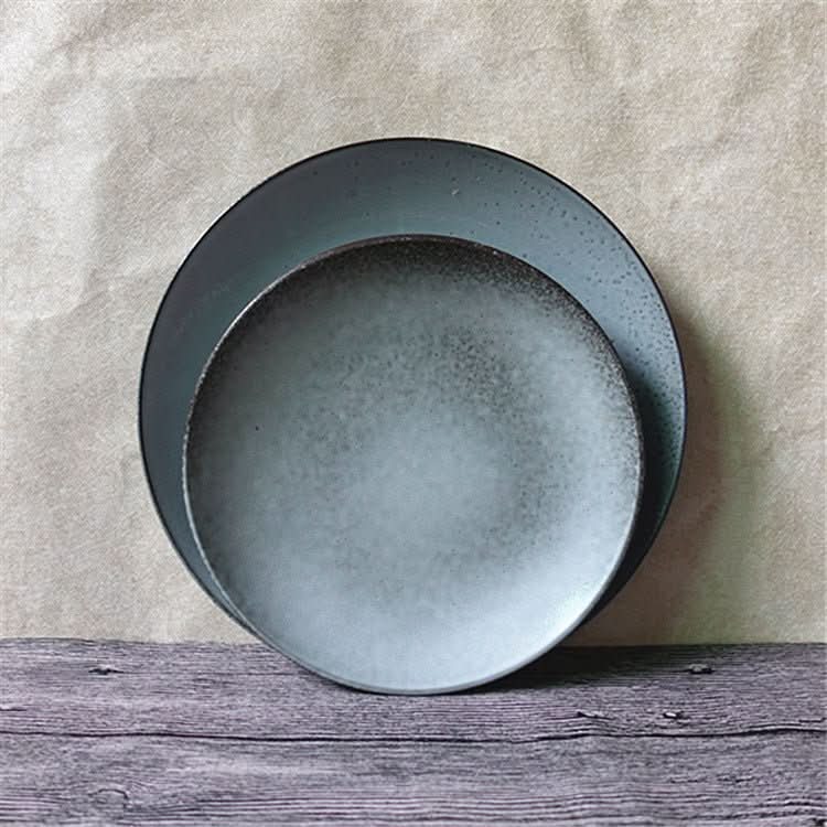 Cyan blue speckled ceramic dinnerware set, two plates stacked on wood.