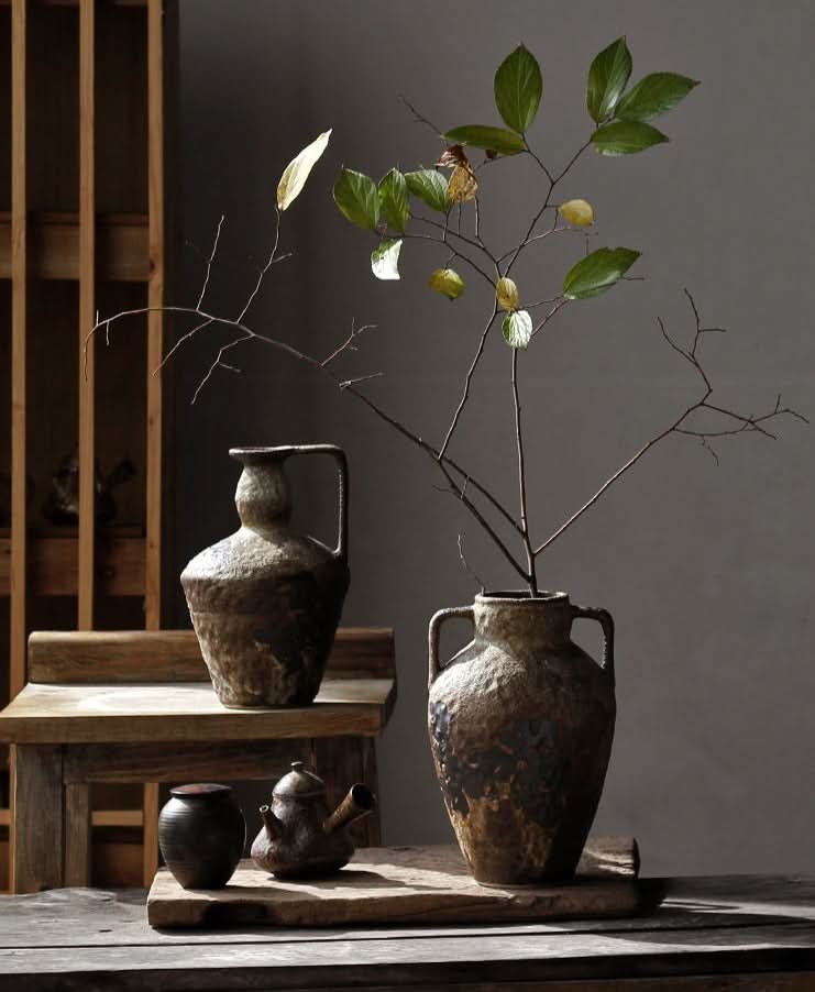 Wabi-sabi small ceramic vase with textured finish in earthy tones on a wooden surface.