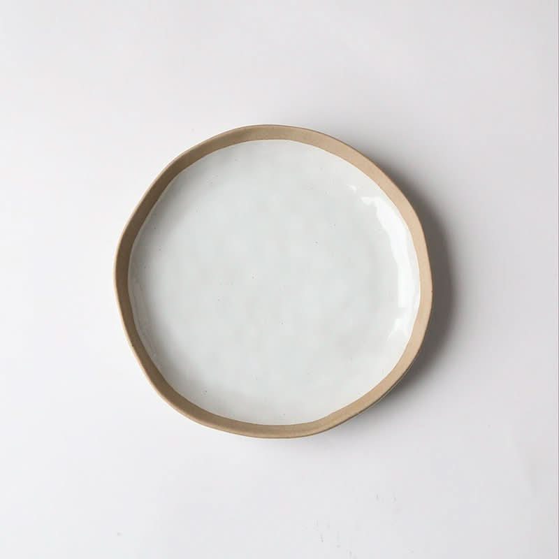 Irregular clay Japanese dinner plate, white with tan rim.