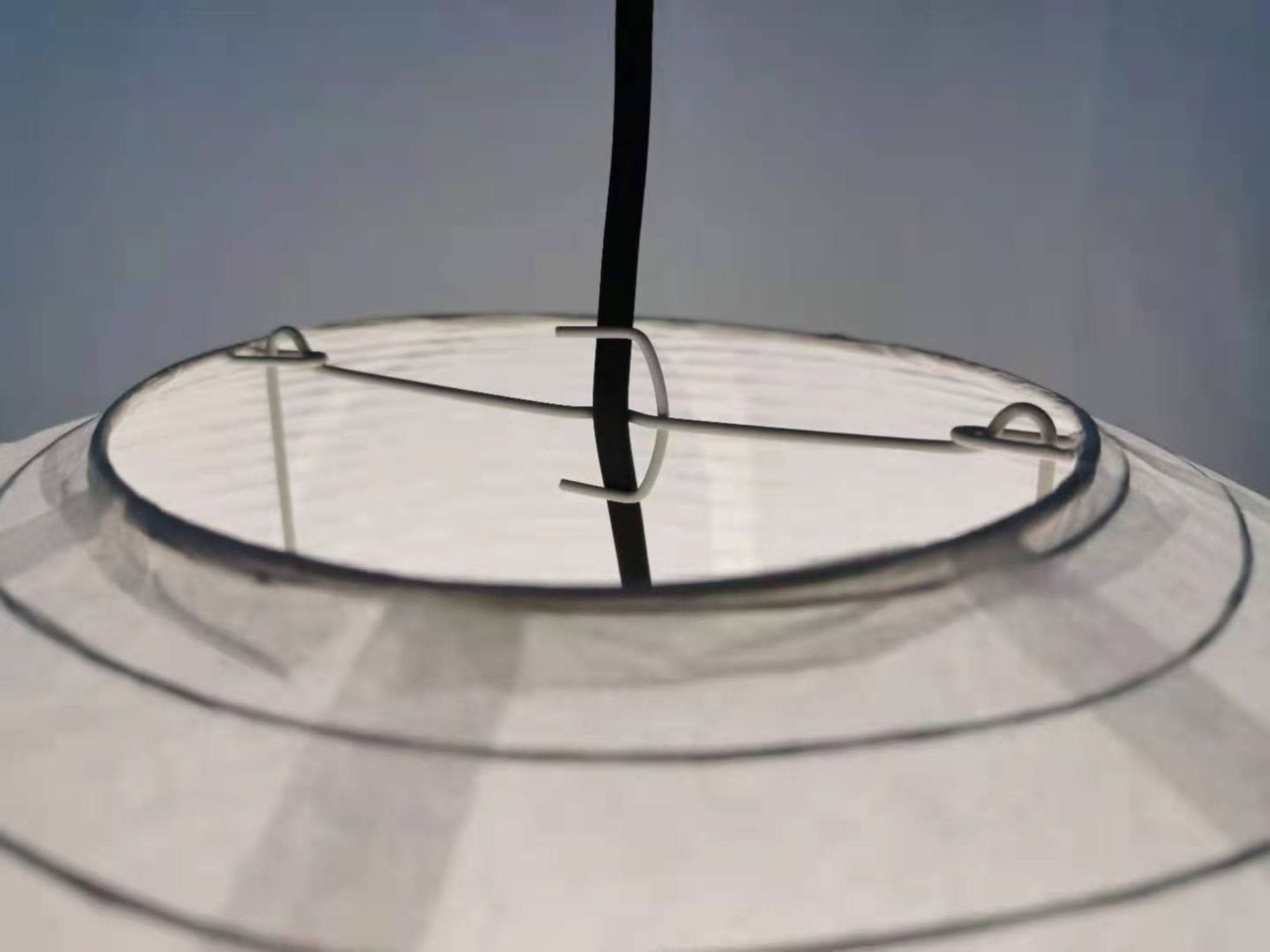 White dome paper ceiling lampshade with black cord and metal frame detail.