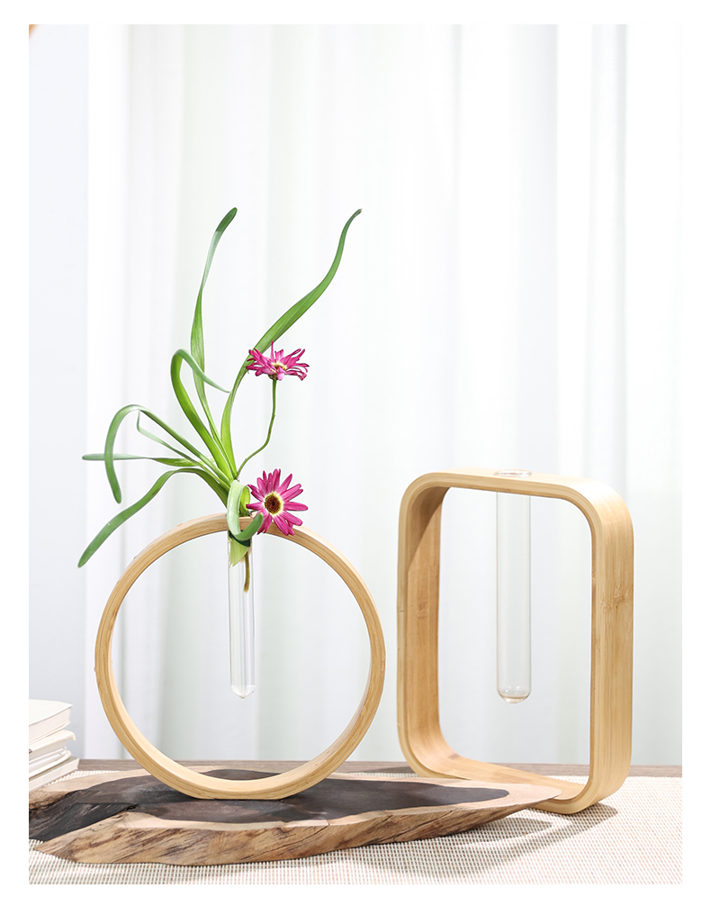 Modern bamboo Wall Flower Vase with pink flowers and green leaves on rustic wood.