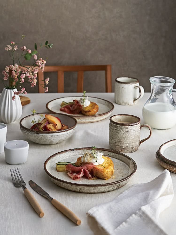 Clay Ceramic White Glazed Dinnerware Set with food, mugs, and carafe on a table.