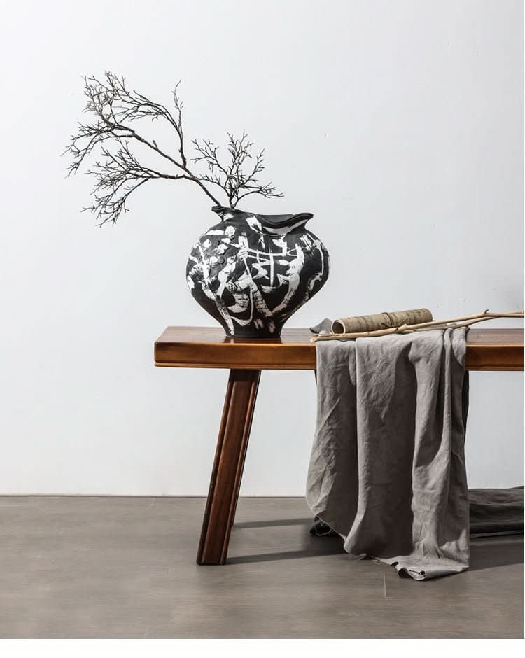 Handmade Wabi Sabi ceramic vase with branches, home decor on wooden table with grey cloth.