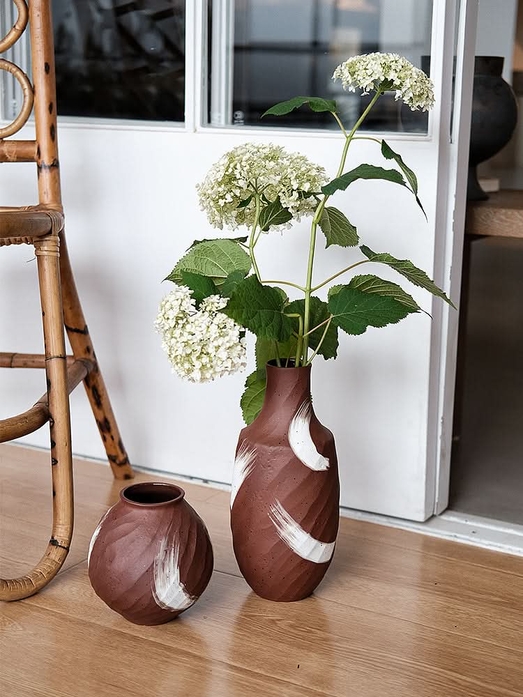 Brown vase with brushed stroke detail, holding white hydrangeas. Home decor accent.