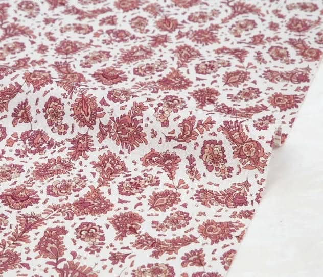 Close-up of white Muslin Floral Fabric with a detailed pink paisley pattern.