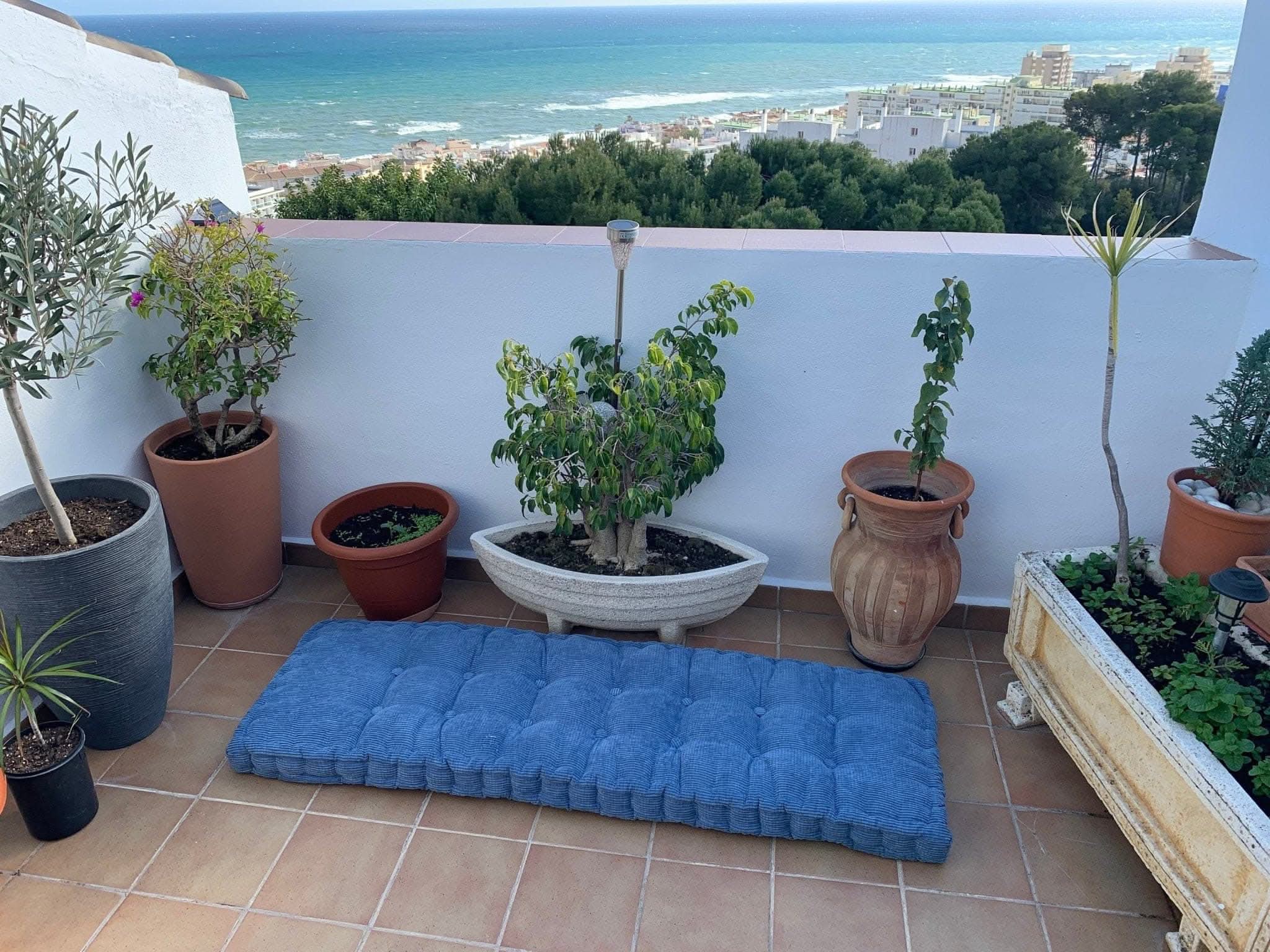 Blue corduroy custom window seat cushion on a tiled balcony with sea view.