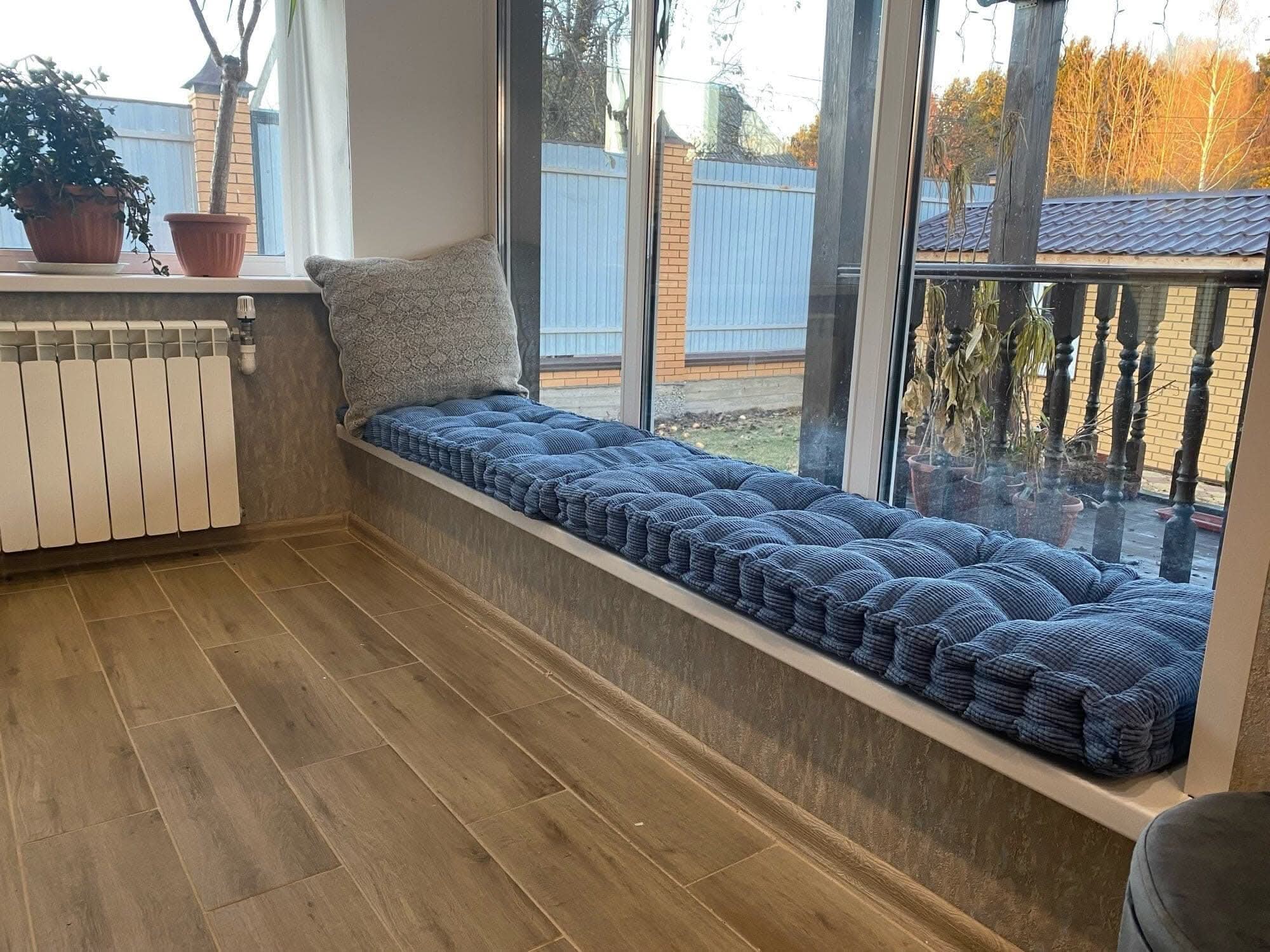 Blue corduroy custom window seat cushions with textured gray pillow on window sill.