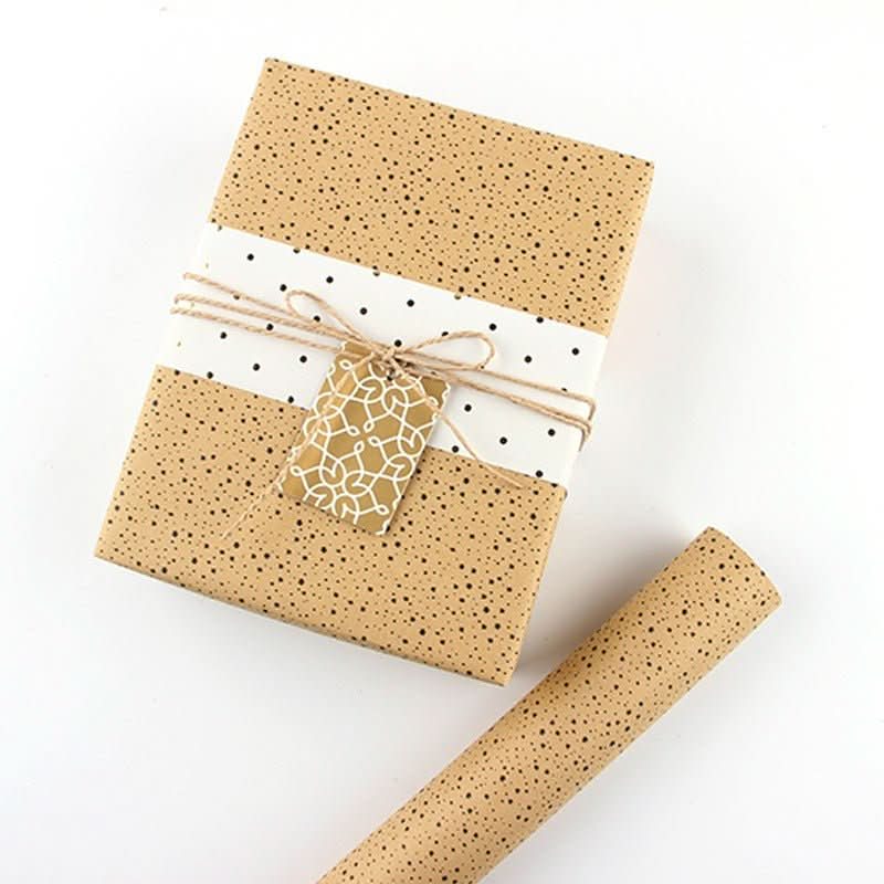 Brown polka dot gift paper wraps a box with a white band & gold tag. A roll of gift paper sits beside it.