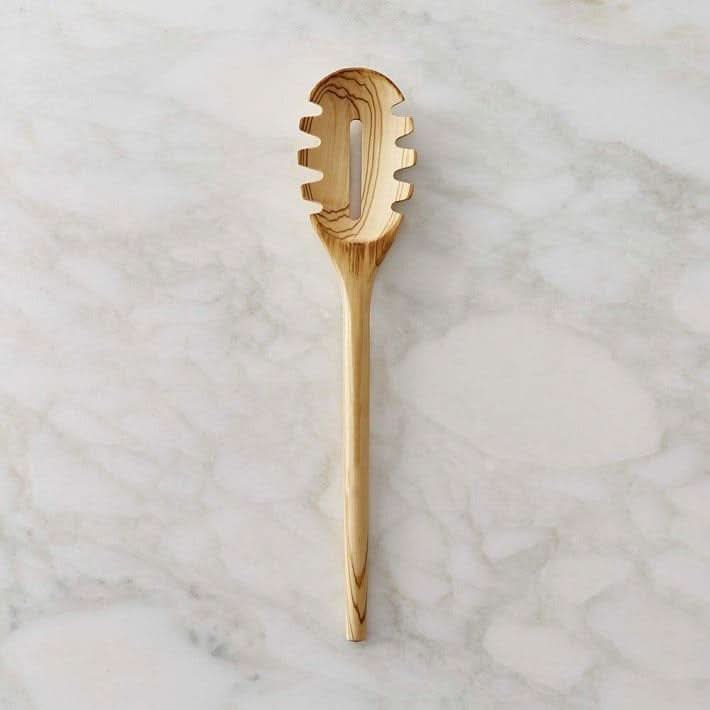 Wooden spaghetti fork spoon with a natural grain on a marbled background.