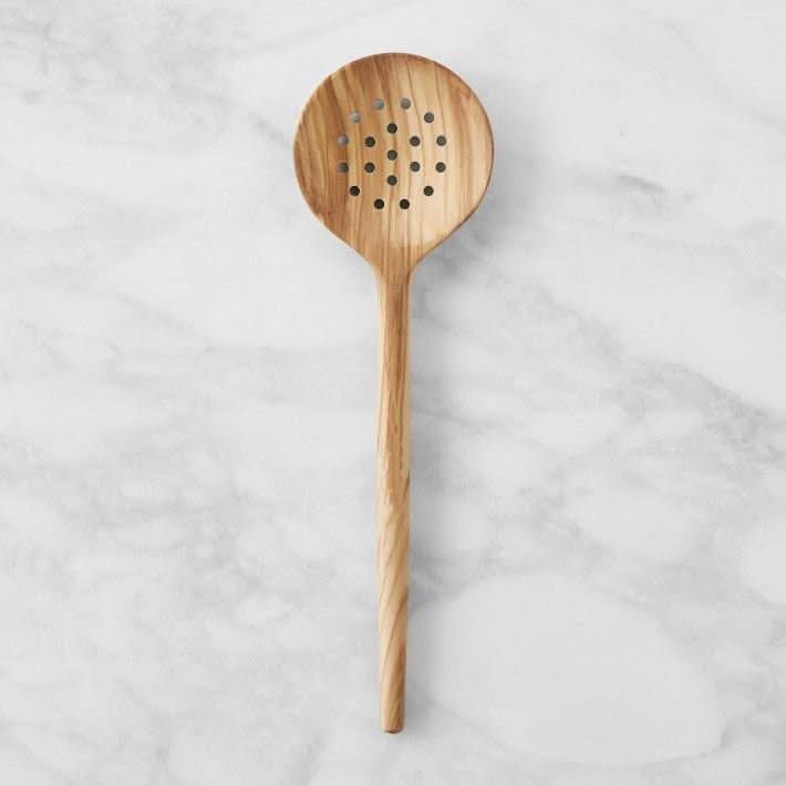 Wooden olive spoon with holes on marble background. Handle olive spoon and set wood cutlery packs.
