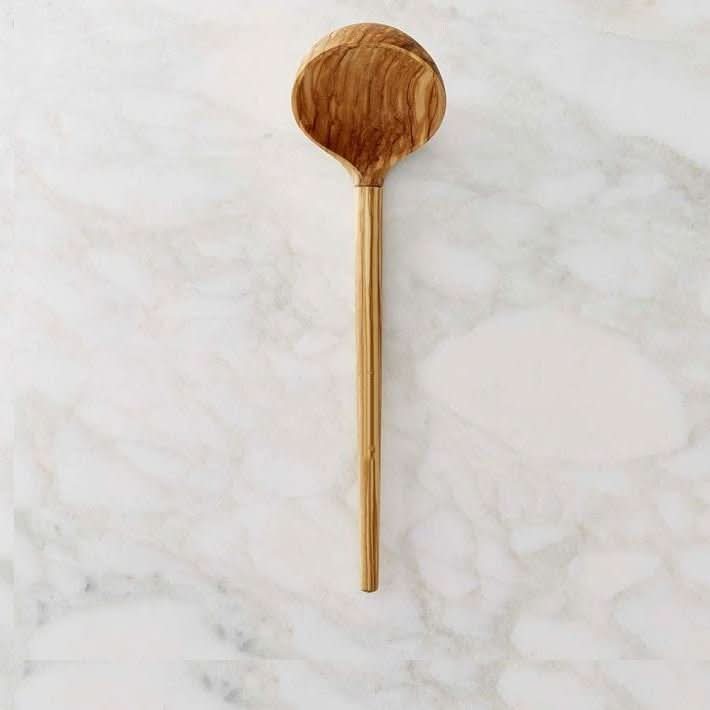 Wooden handle olive spoon on white marble background, ideal for wedding cutlery sets.