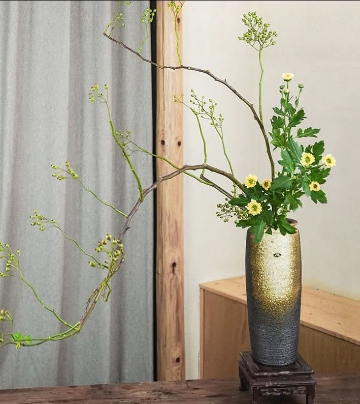 Handmade Japanese kiln glazed vase with golden and grey finish, holding a Zen flower arrangement.