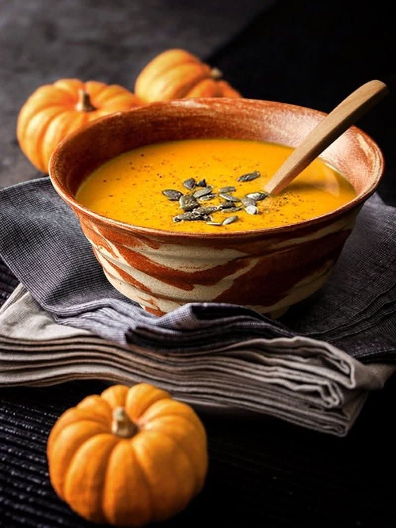Ceramic ramen bowl, 47oz, with orange marble effect, holding soup with pumpkin seeds.