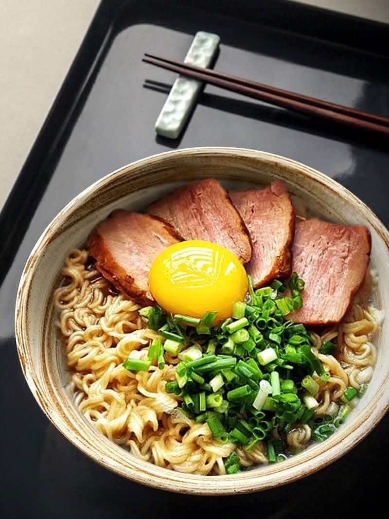 Ceramic Ramen Bowl 47oz with marble effect holding ramen, sliced pork, egg yolk, and green onions.
