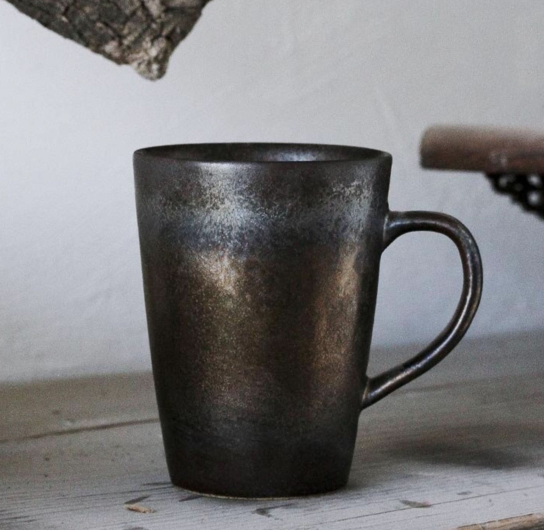 Metallic glazed handmade pottery mug on wooden surface