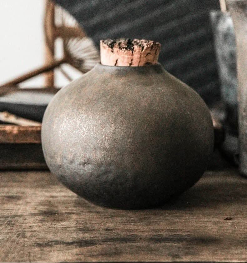 Retro dark ceramic airtight jar with cork lid on wooden surface.