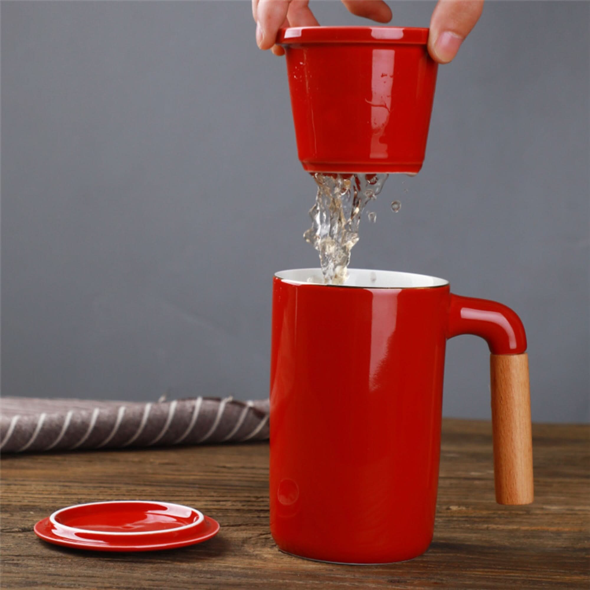Red ceramic Japanese mug 2x1 with wooden handle, lid, and strainer being filled with water.