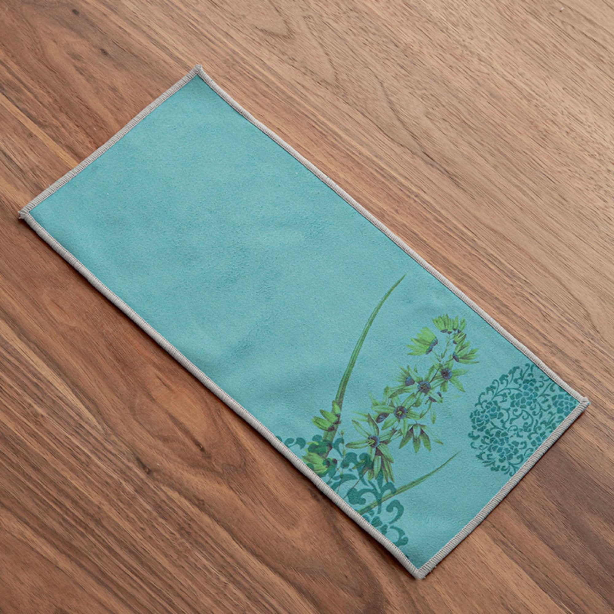 Teal Japanese tea towel with Ukiyo-e style floral print on wooden background.