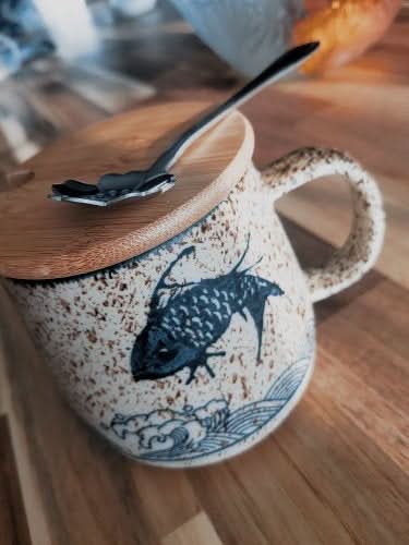 Japanese mug set with fish design, bamboo lid, and spoon. Modern ceramic pottery.