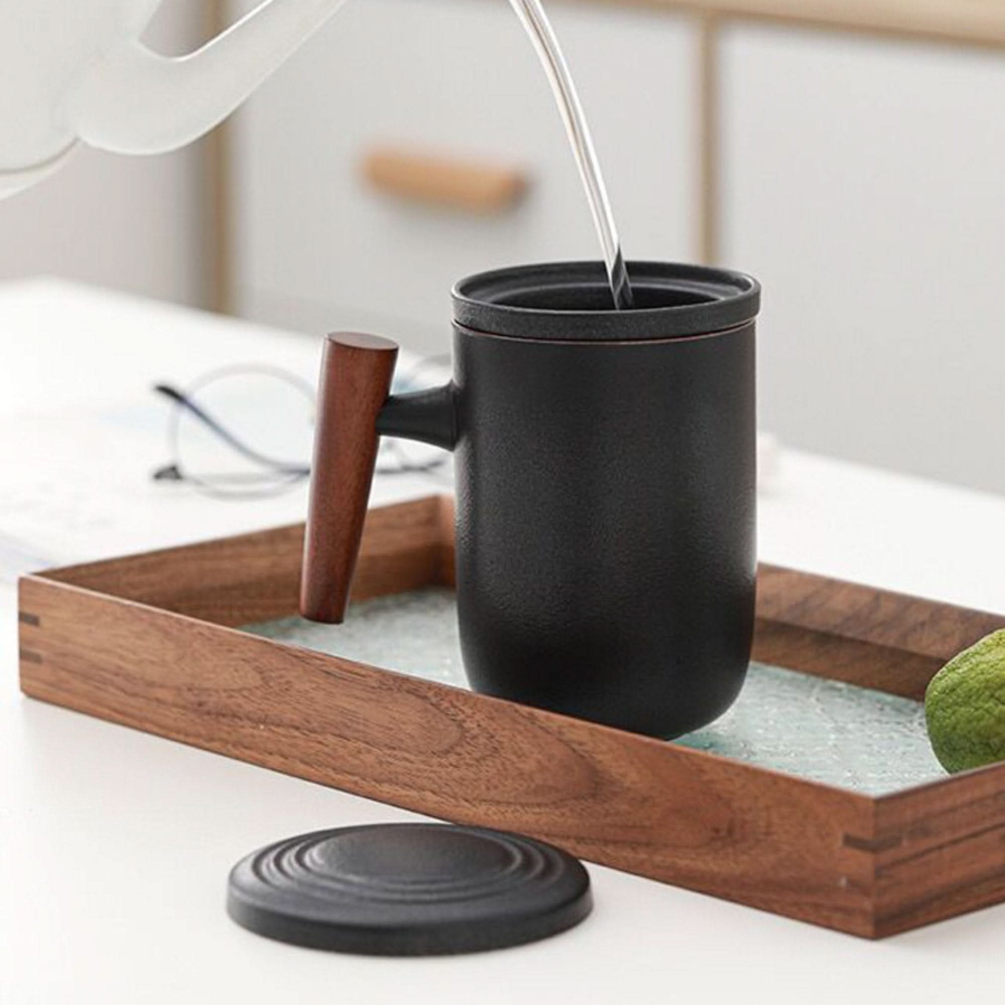 Minimalist Japanese mug, black ceramic with wood handle, on tray.
