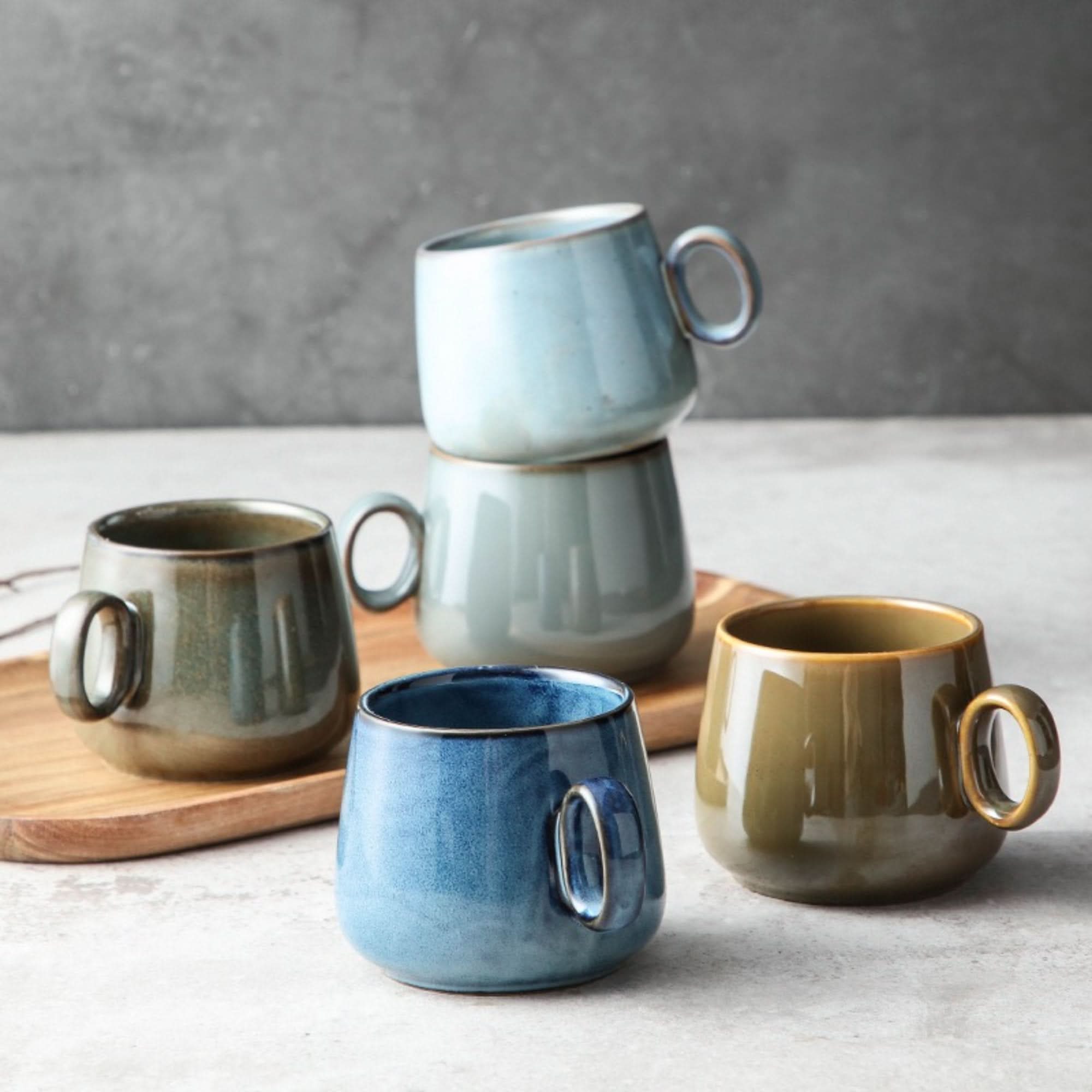 Set of 4 stoneware Retro Mug 2 for 1 in blue, green, and gray on a wooden board.