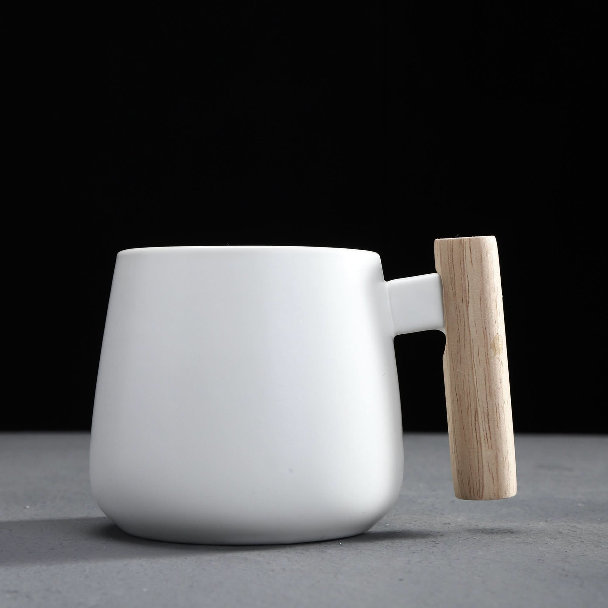 White Japanese style large coffee mug with wooden handle on gray surface