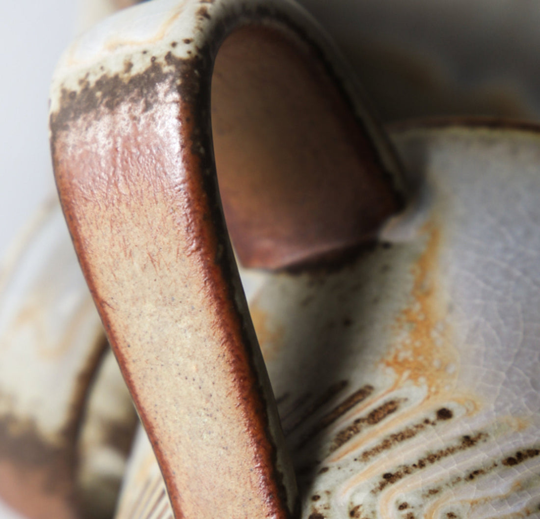 Multi-colored Japanese stoneware mug with carved design.