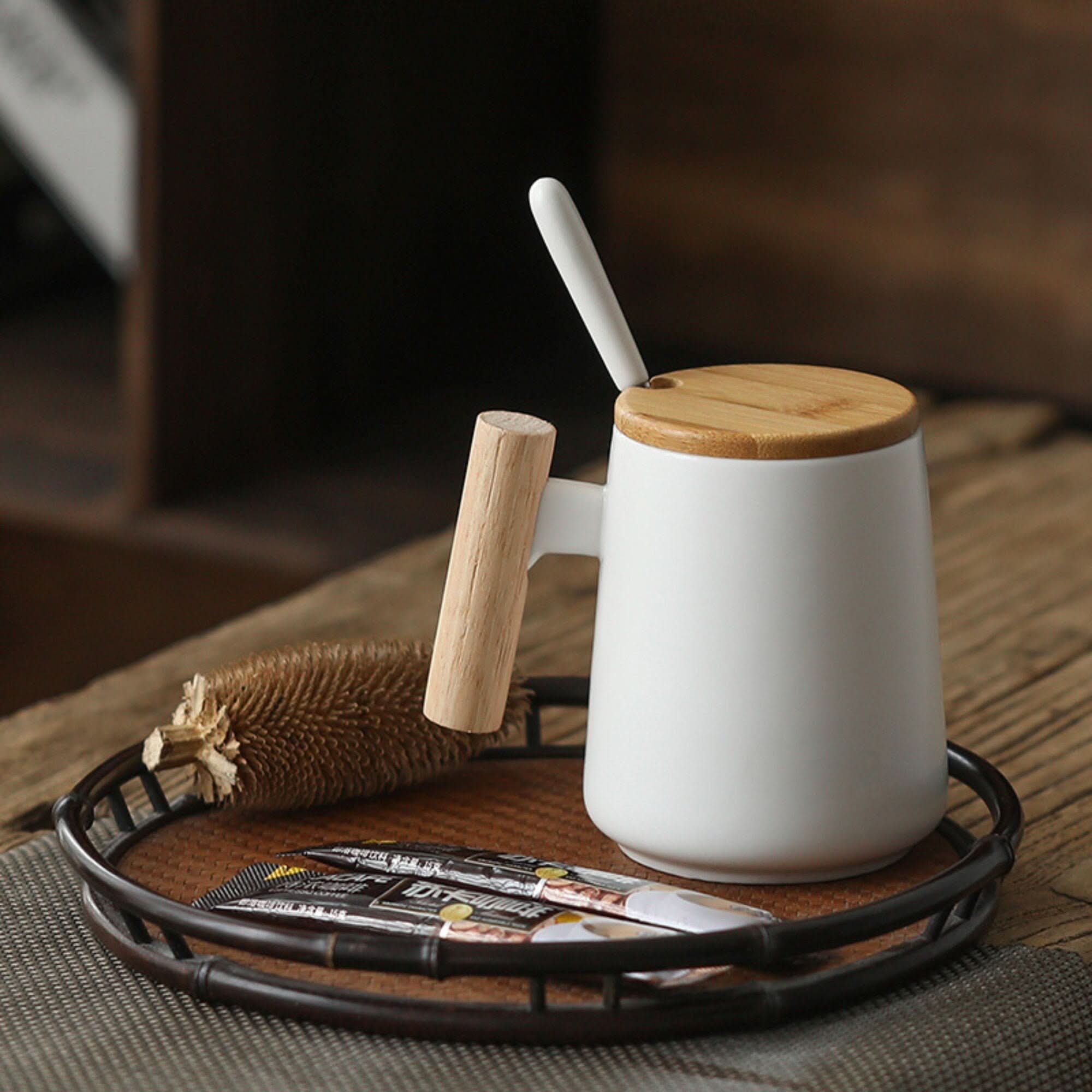 Minimal Japanese style white ceramic coffee mug with wooden handle & lid on a bamboo tray.