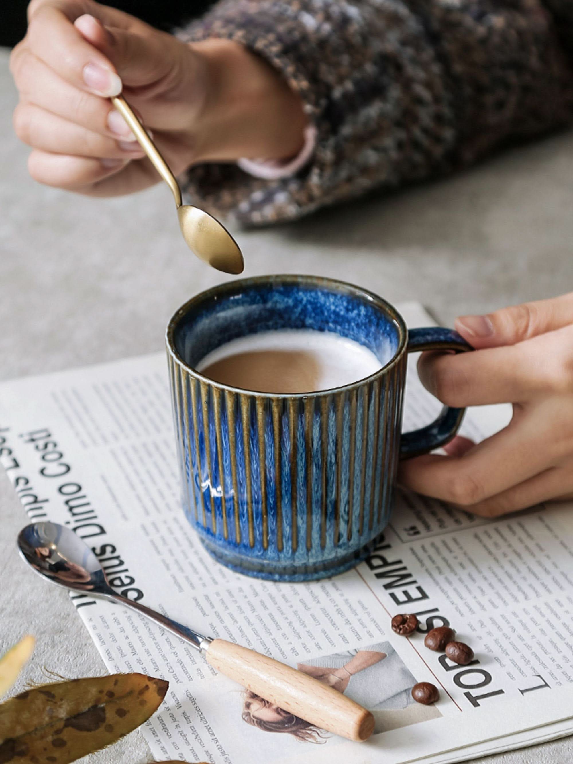 Blue glazed stoneware mug with vertical ribbed texture, filled with coffee.