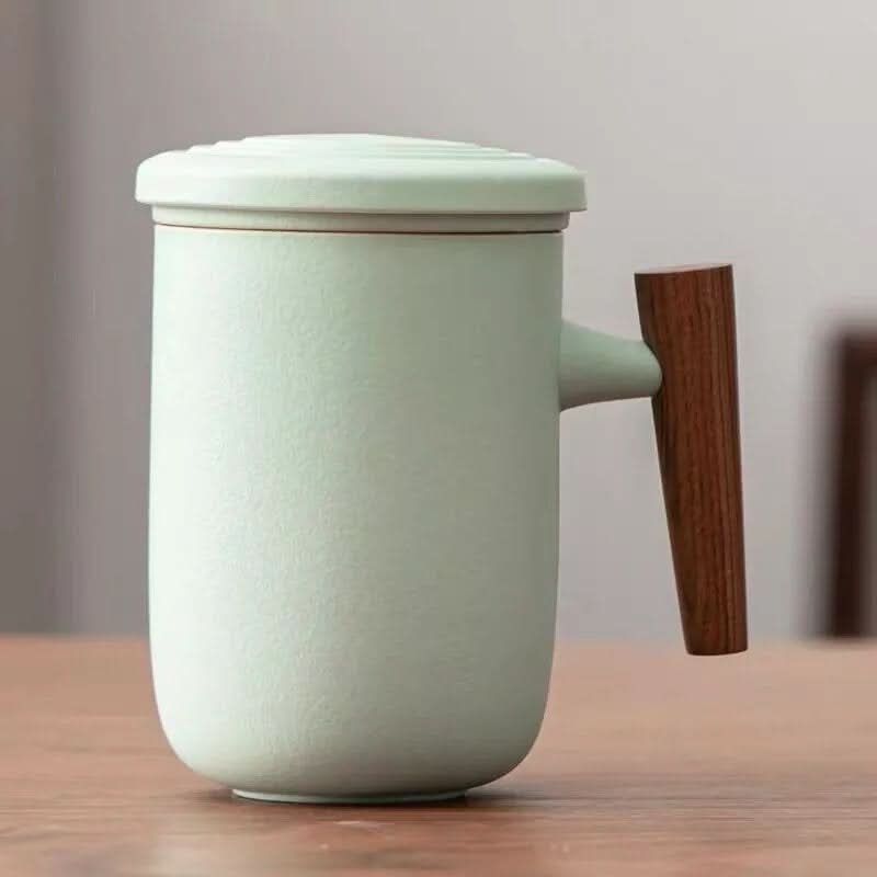 Minimalist Japanese 13.5oz latte mug in matte mint green ceramic with wood handle on table.