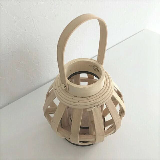 Natural bamboo hand-woven candle holder with a handle on a white surface.