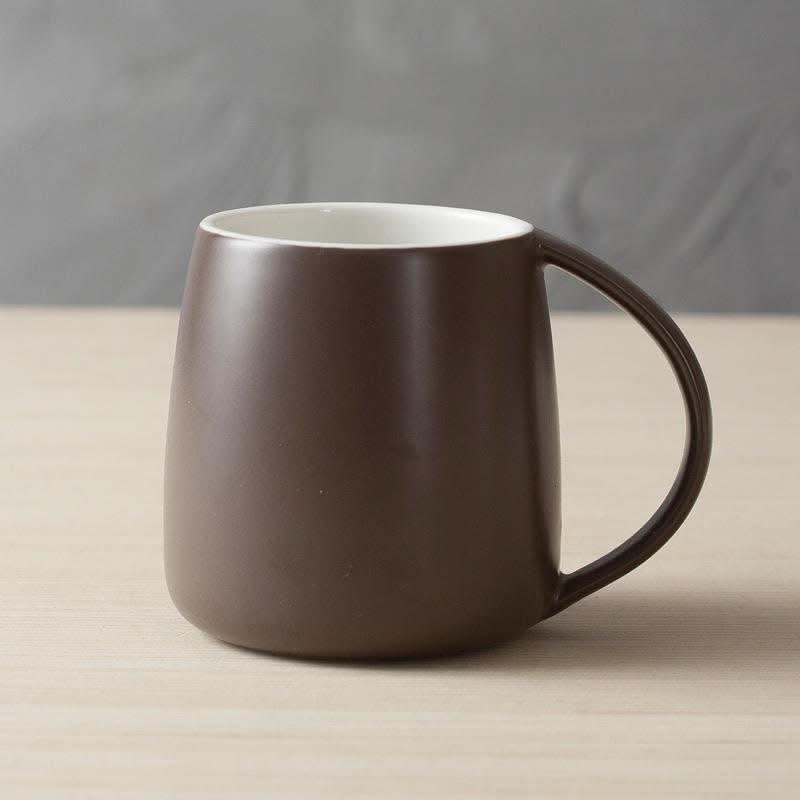 Matte brown Nordic Ceramic Mug with white interior, minimalist design on wooden surface.