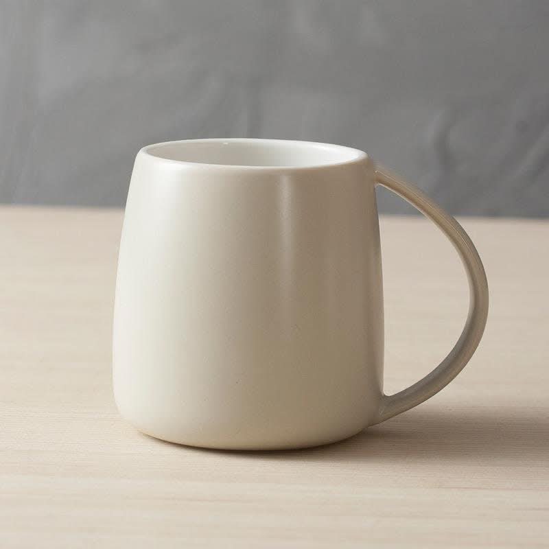 Nordic ceramic mug in cream, minimalist Japanese design on a wooden surface.